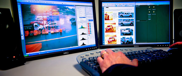 a video workstation with 2 monitors side-by-side displaying images of a parking lot in editing software