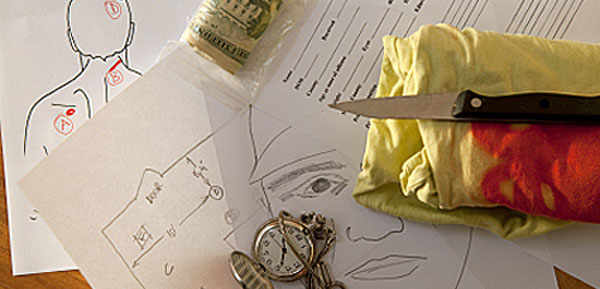 the top of a table, showing a suspect sketch, autopsy report, file folder, bloody shirt, and knife