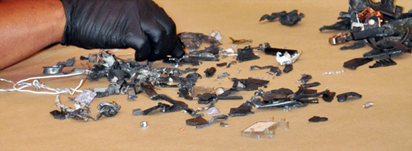 An investigator sifts through small pieces from an exploded IED